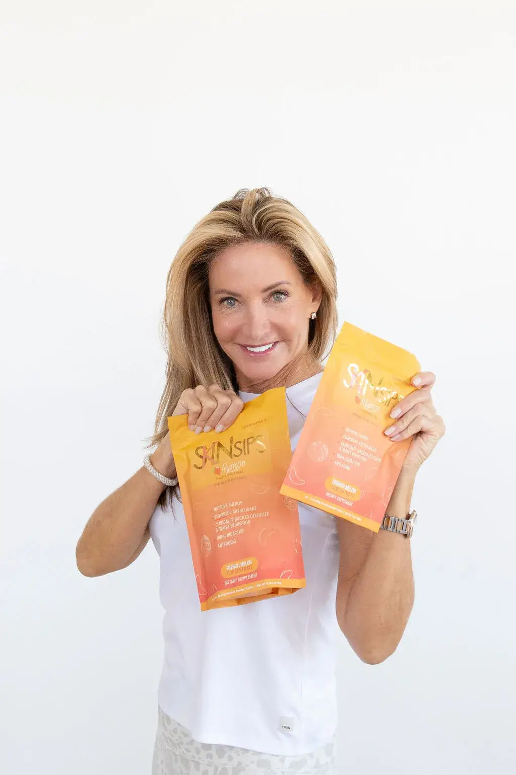 Mary Rankin and another woman smiling while holding SkinSips antioxidant drink mix pouches.