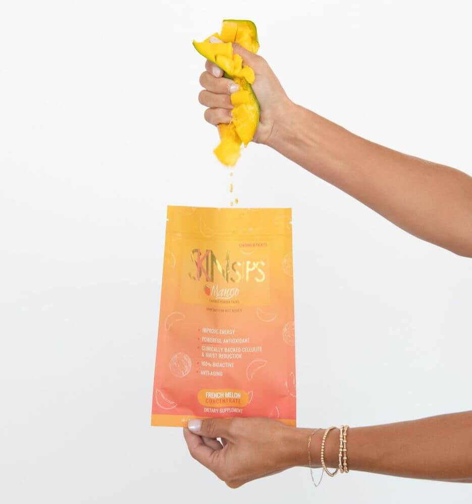 Hand squeezes fresh mango pieces over SkinSips mango pouch dietary supplement.
