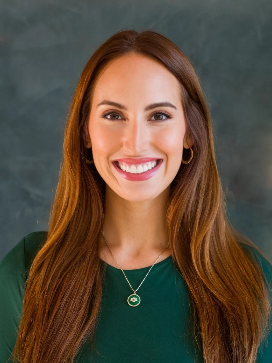 Headshot of Anne Stanard smiling with long brown hair wearing green top and necklace.