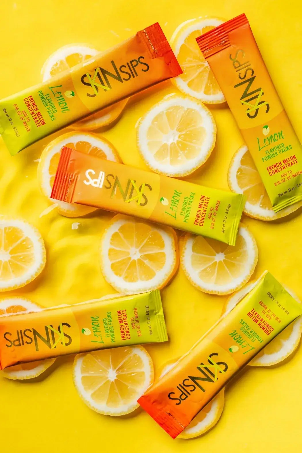 SkinSips lemon flavored powder sticks displayed on yellow background with sliced lemons.