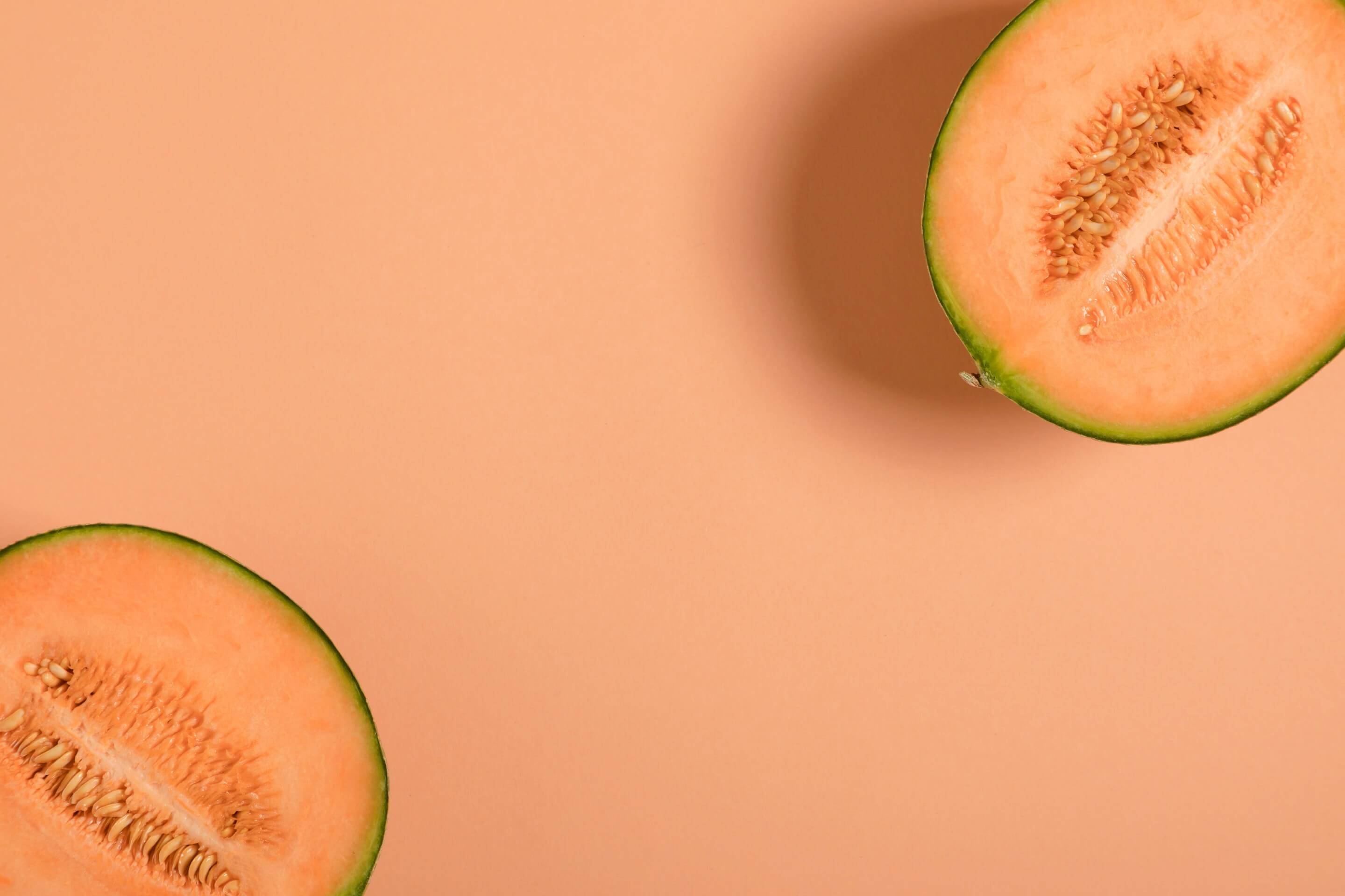 Two cantaloupe halves on a peach background