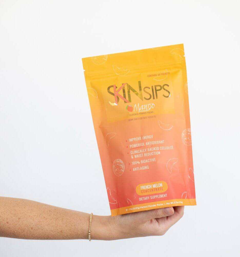 Hand holding SkinSips mango pouch dietary supplement against white background