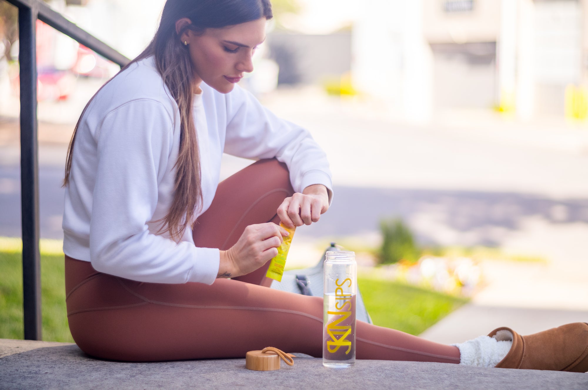 Girl opening SkinSips packet and pouring into SkinSips bottle